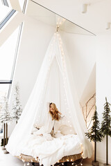 Adorable woman sit on canopy bed, smiling, stretching, gorgeous lady relaxing, spend winter holidays at home, enjoy vacations, New Year celebration, Christmas morning concept