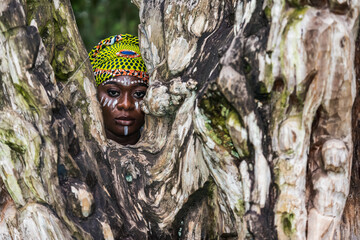 Ghana woman with tribe painting behind a large wooden trunk. Ghana West Africa