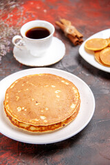 Top view of American homemade pancakes on white plates and a cup of tea on mixed color table