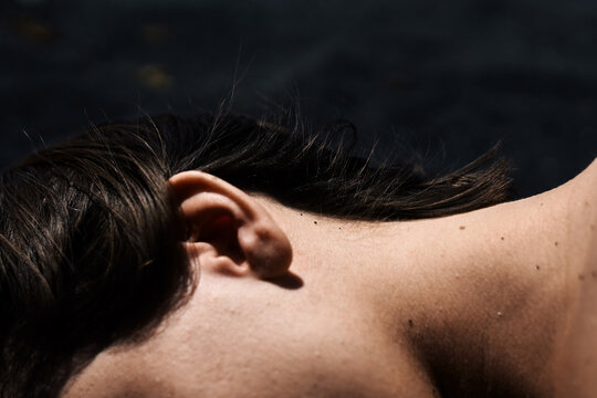 woman ear and neck close-up lying on the black sand beach