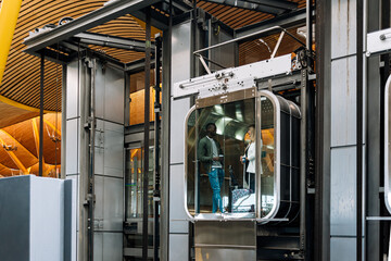 young interracial couple on a glass elevator at the airport with luggage