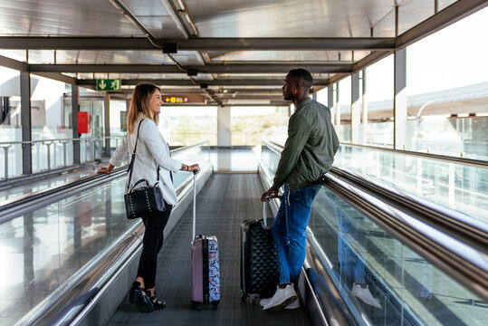 young multiracial couple on the walkway at the airport with luggage