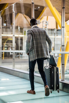 man walking at the airport using mobile phone with headphones