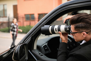 Private detective with camera spying from car