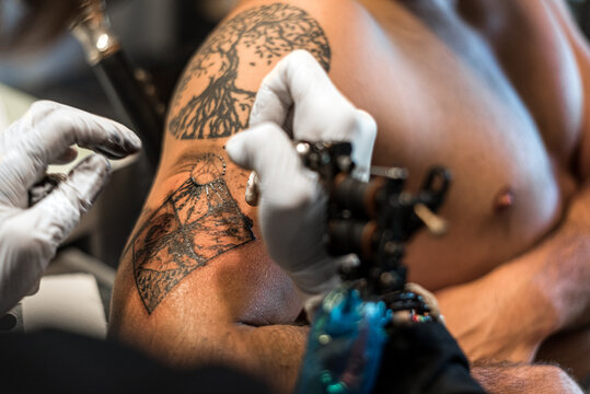 Crop person making four elements tattoo on arm man