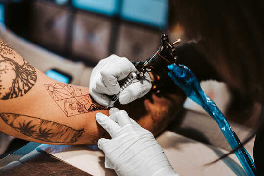 Crop person making four elements tattoo on arm man