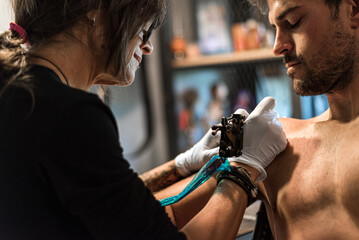 tattoo artist woman making tattoo for man