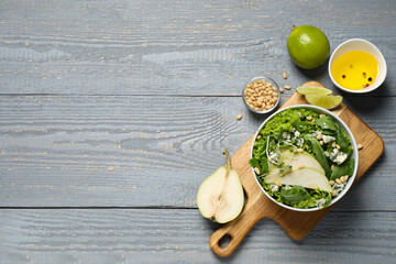 Obraz na płótnie Canvas Fresh salad with pear and ingredients on grey wooden table, flat lay. Space for text