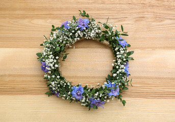 Beautiful flower wreath on wooden background, top view