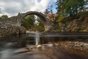 Fototapeta premium old stone bridge over red river in scotland at autumn