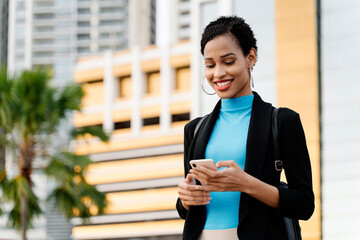 Afro woman using mobile phone in the street