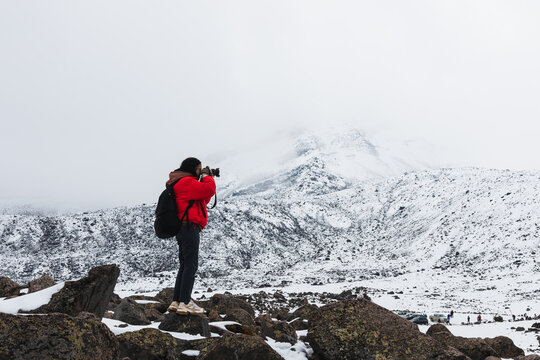 Woman photographing a volcano with snow
