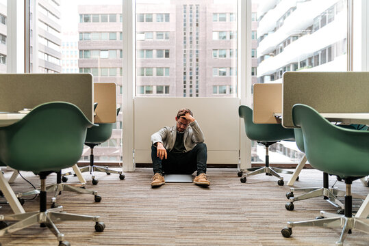 Frustrated young man sitting on floor in office