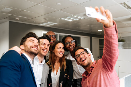 Bright businessman taking selfie with colleagues in office