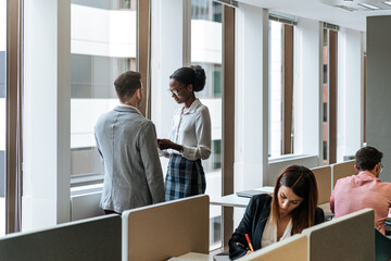 Female executive with report talking to male manager at busy office