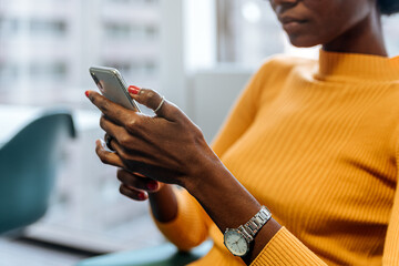 Faceless ethnic lady using smartphone at office