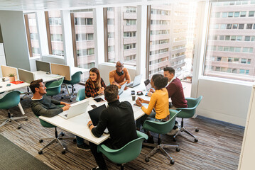 Office employees at conference desk chatting in office