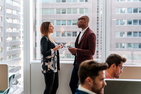 Female executive with report talking to male manager at busy office