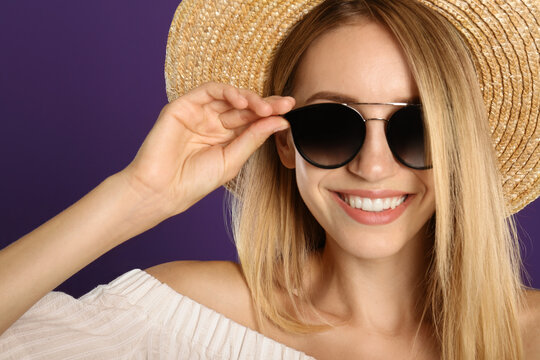 Beautiful woman in stylish sunglasses on purple background, closeup