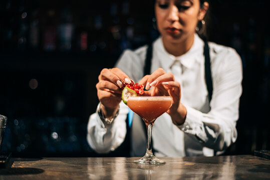 Blurred bartender decorating cocktail in pub