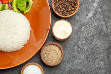 Half shot of vegan dinner with rice and different types of vegetables with spices on dark table
