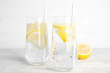 Fototapeta na wymiar Soda water with lemon slices and fresh fruit on white wooden table