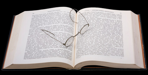 Close-up of reading glasses on an open book, with Old Church Slavonic type on a black background