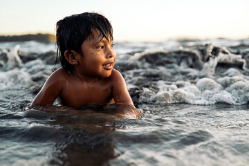 Portrait of a panamanian kid playing alone at the beach with the waves