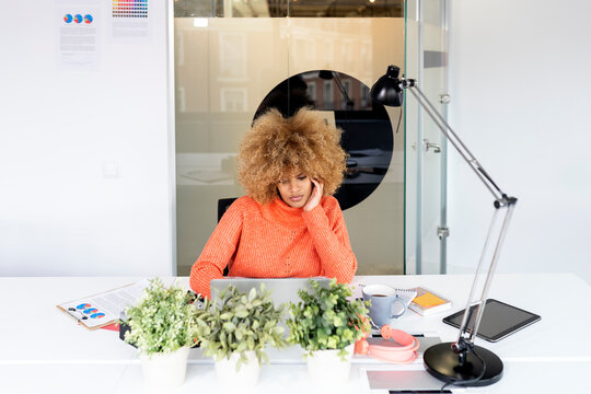 Black woman using laptop in office.