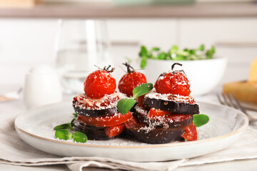 Baked eggplant with tomatoes, cheese and basil on kitchen table, closeup