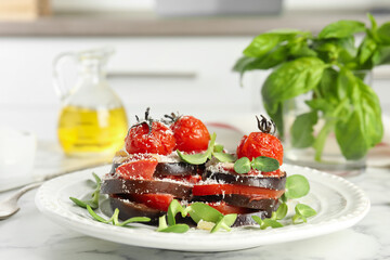 Baked eggplant with tomatoes, cheese and basil on kitchen table