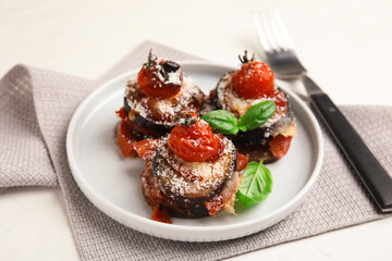 Baked eggplant with tomatoes, cheese and basil served on white wooden table
