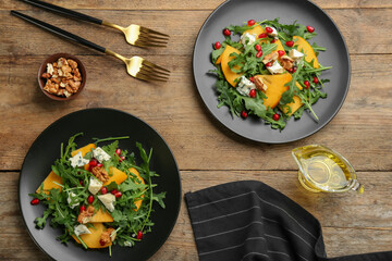 Delicious persimmon salad with pomegranate and arugula served on wooden table, flat lay