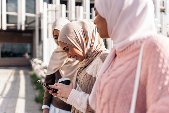 Three muslim women looking at smartphone.