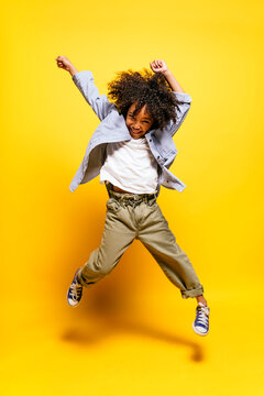 Black kid jumping in studio smiling.