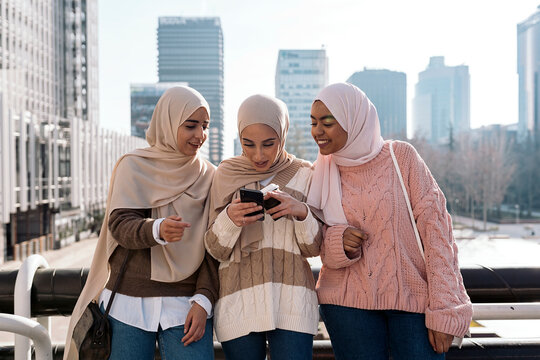 Three muslim women looking at smartphone.