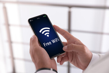 Man using mobile phone connected to WiFi indoors, closeup