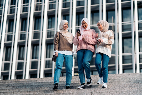 Three muslim women walking down stairs.