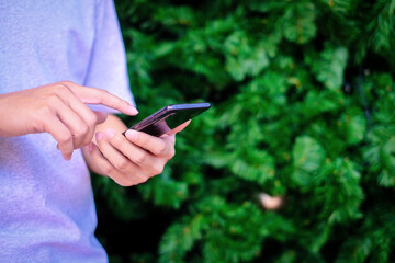 Man holding smartphone with christmas tree background, Technology concept.