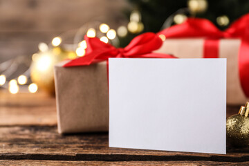 Blank Christmas card and golden bauble on wooden table, closeup. Space for text