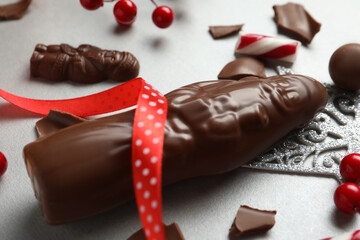 Composition with chocolate Santa Claus candies and Christmas decorations on light grey table