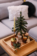 Composition with decorative Christmas tree and reindeer on wooden tray near sofa