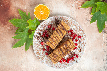 top view cake slices with choco icing and red berries on light floor biscuit cake sweet