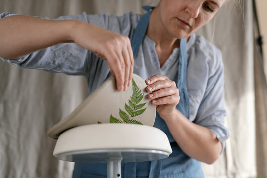 Female ceramist crafting clay product with leaf pattern