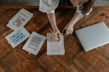 Crop artisan drawing rug sketches in notepad