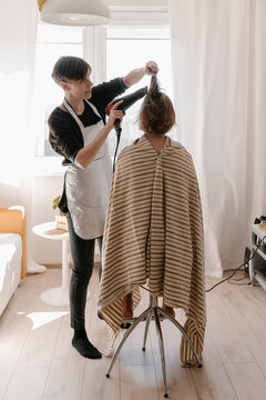 Hairdresser drying hair of client