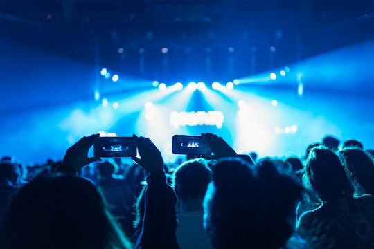 Silhouettes of concert crowd in front of bright stage lights