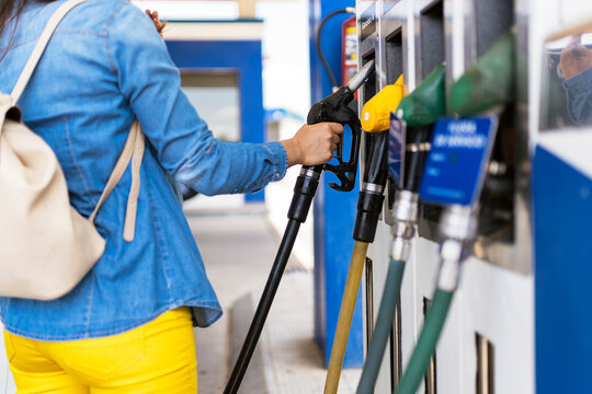 Unrecognizable woman holding fuel nozzle to refuel oil for car