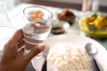 Hand holding a glass of water with indonesian food background