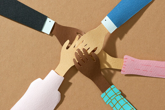 Friends with stack of hands showing unity and teamwork.